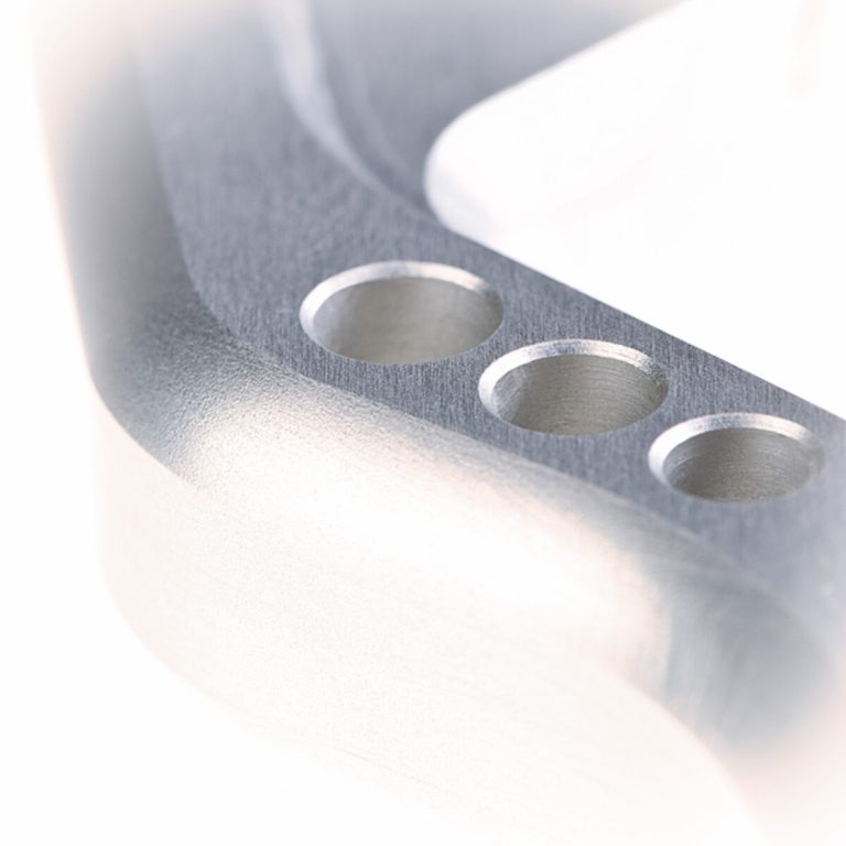 Detailaufnahme eines metallischen Teils mit Bohrungen.