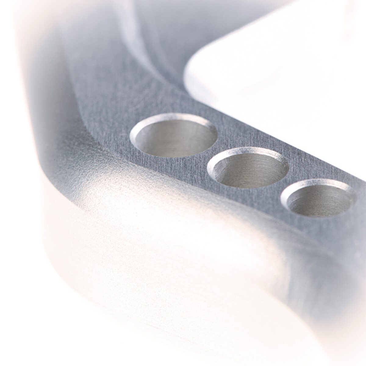 Detailaufnahme eines metallischen Teils mit Bohrungen.