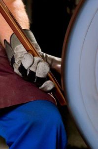 Handwerker schleift Werkzeug an Schleifmaschine